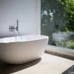 Weiße Keramikbadewanne steht neben klarer Glaswand - In diesem Beitrag erfahren Sie wissenwerte Infos zum Thema: Fugen? Nein danke! – Das Bad ohne Fliesen als Wohntrend.